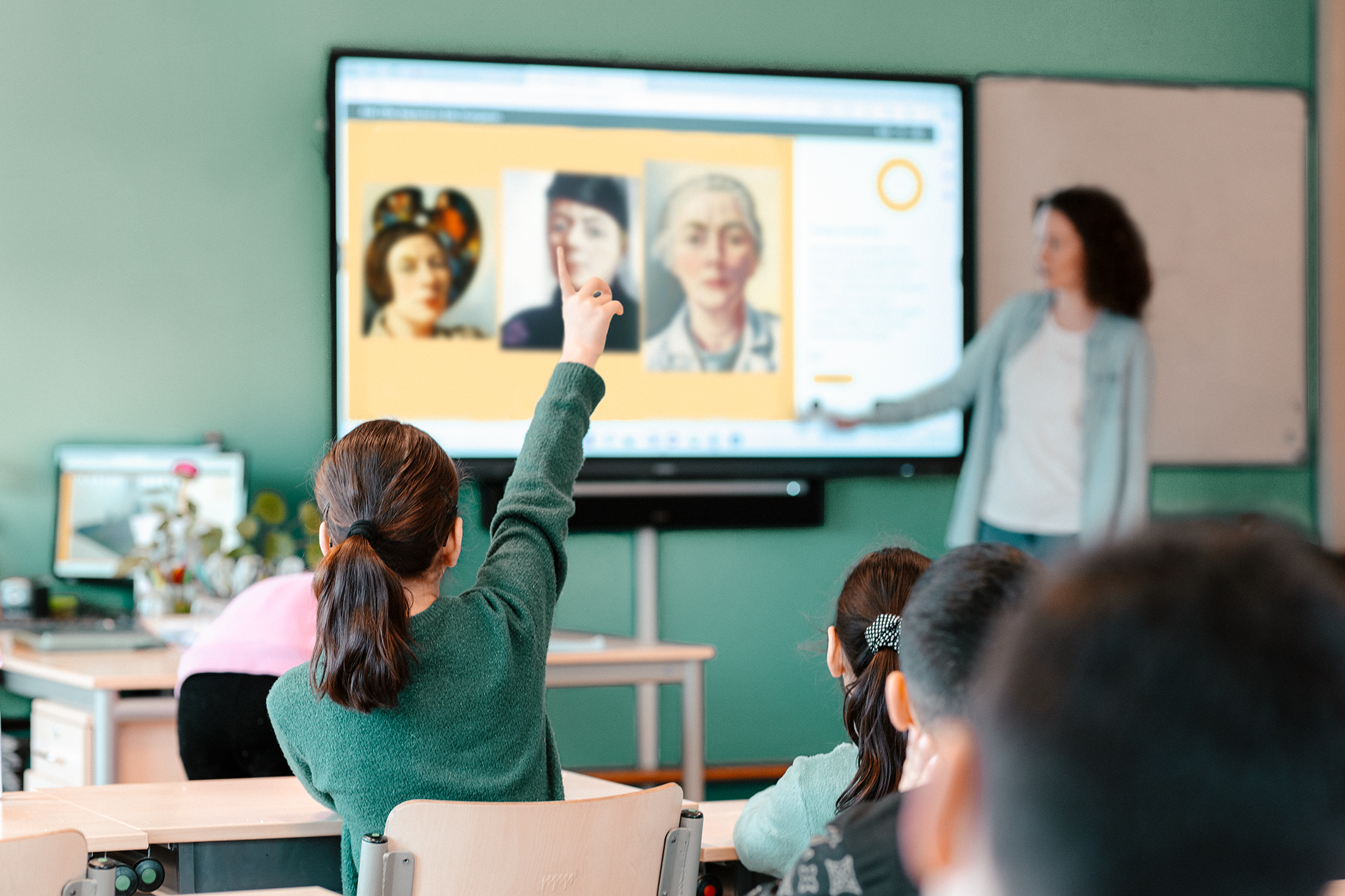 leerkracht voor digibord met leerling op de voorgrond